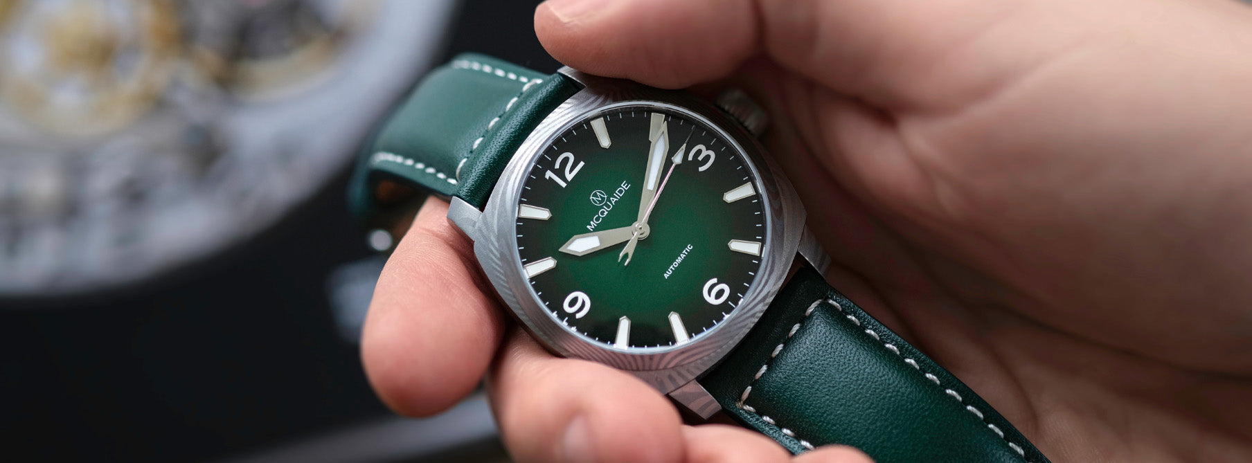 Hand holding the McQuaide C1 Evergreen with a blurred background