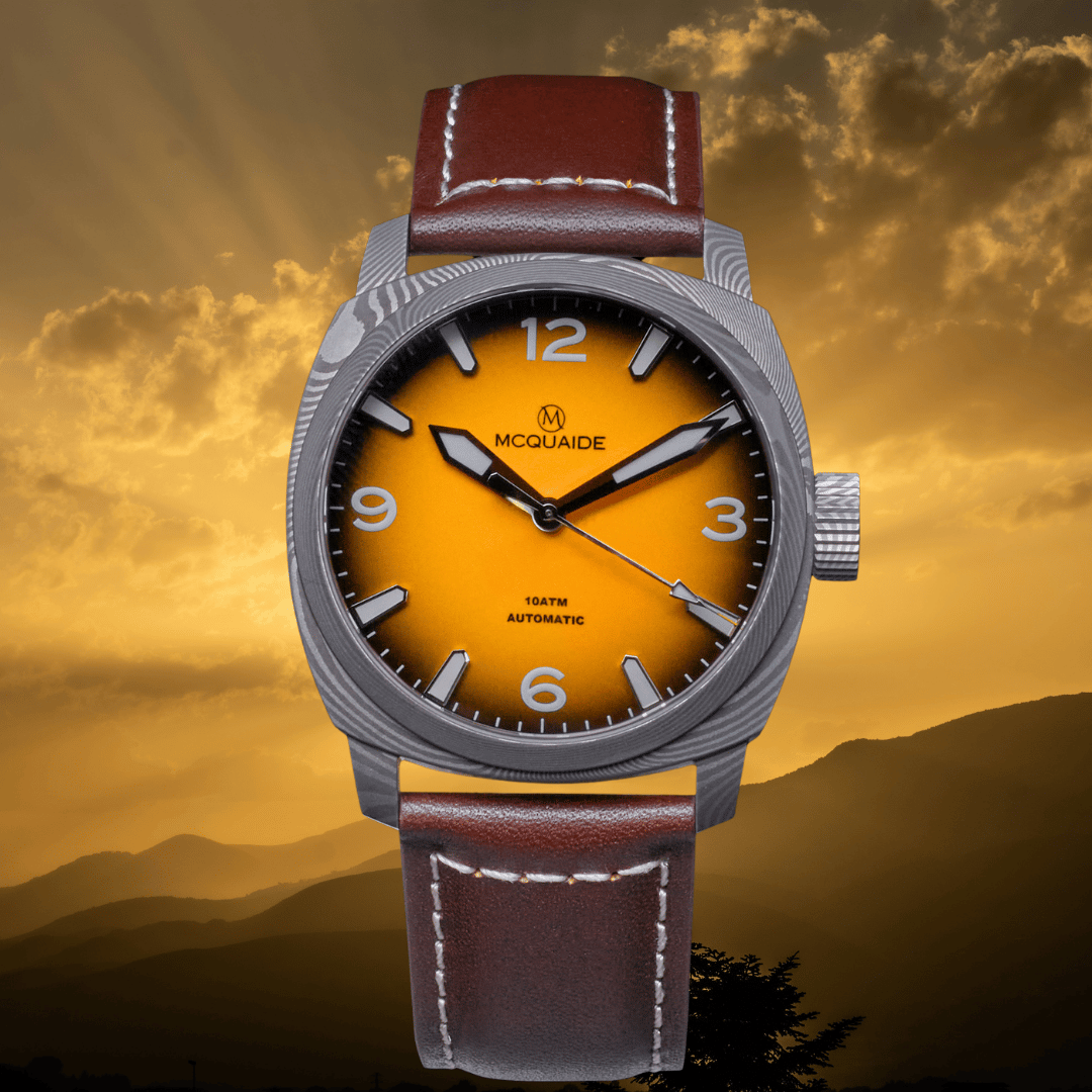 A McQuaide 100m automatic watch with a silver-tone case, a vibrant yellow-to-orange gradient dial, and a brown leather strap, set against a dramatic golden sunset background.