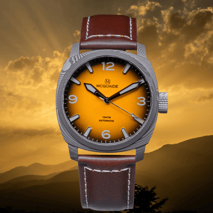 A McQuaide 100m automatic watch with a silver-tone case, a vibrant yellow-to-orange gradient dial, and a brown leather strap, set against a dramatic golden sunset background.